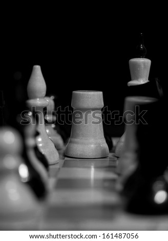 white chess bishop surrounded by black chess pieces on a chessboard