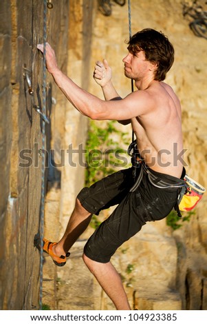 young rock climber  climbs the cliff with a belay
