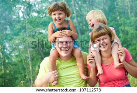 family lifestyle portrait of a mum and dad with their children having good time in the green  park