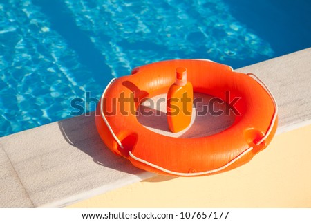 bright orange life preserver floating on the coast swimming pool and sunblock