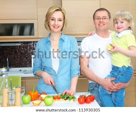 Happy family is preparing a healthy dinner in the kitchen. Mother cuts  vegetables