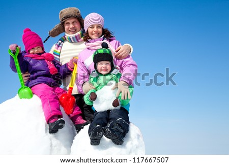 Happy couple with two children making big snowman