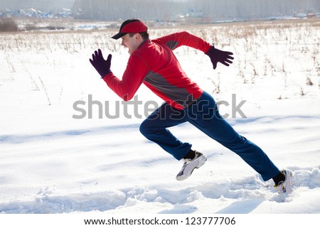 Athletic  man running in winter day on snow road