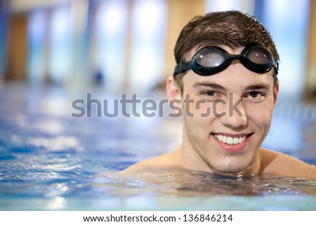 Happy attractive man swimming in blue water in  swimming pool