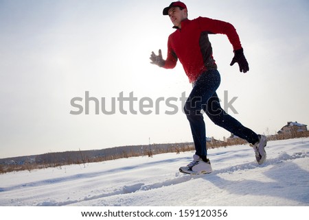 Athletic  man running in winter day on snow road