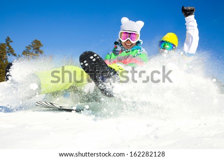couple of young people  slide downhill together on mountain holiday