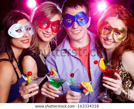 young company in mask celebrates holiday with a cocktail in hand