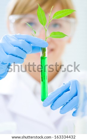 Woman scientist holding a test tube with plant. Ecology