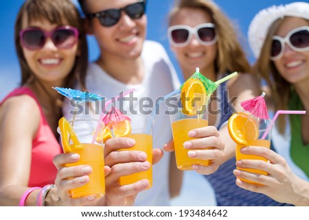 young people with cocktails in hand on the beach