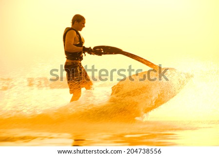 strong man drive on the jetski above the water at sunset .silhouette. spray.