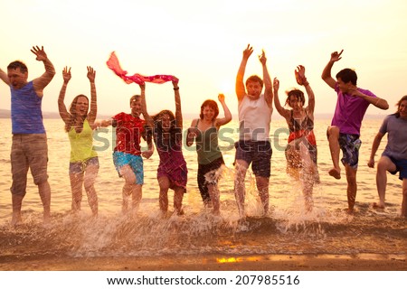 group of happy young people jumping at the beach on  beautiful summer sunset