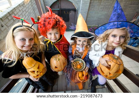 children in halloween costumes with pumpkin walk in guests