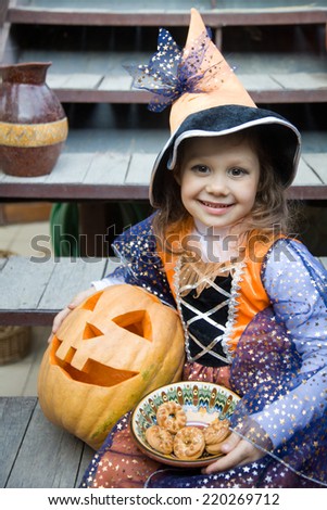 girl in a witch costume with halloween pumpkin on holiday