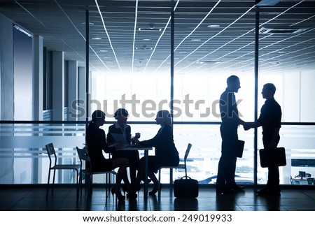 Several silhouettes of businesspeople interacting  background business center