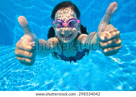 little girl dives into the water and shows the gesture OK