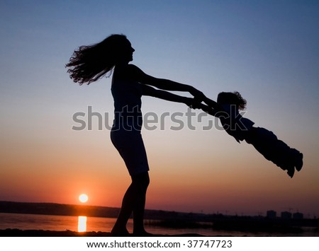 Silhouette of mother which turns the child against a sunset and water