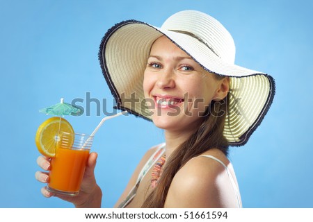 Portrait attractive brunette woman in big hat with orange drink and on the blue background