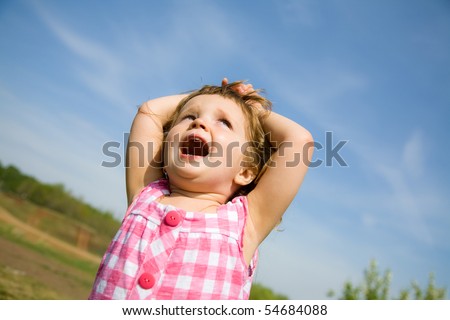 screaming three year old girl raised her hands behind her head and looks at the sky