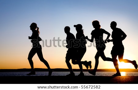 group of young people runs at the beach on beautiful summer sunset