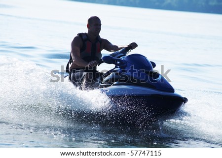 strong man drive on the jetski above the water at sunset .silluet. spray.
