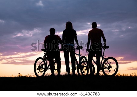Silhouette of three cyclists on the background of a beautiful sunset