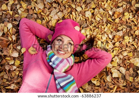 Horizontal image of a beautiful young woman lying in a pile of leaves.