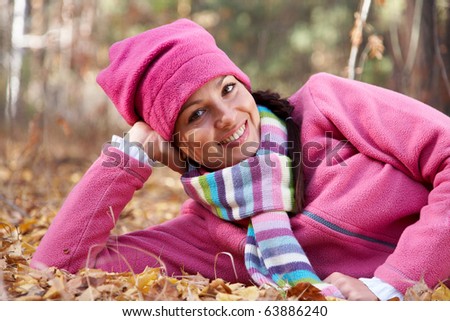 Horizontal image of a beautiful young woman lying in a pile of leaves.