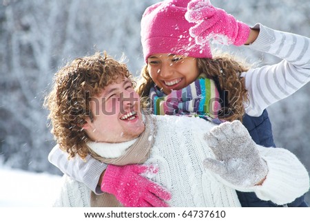 A young playful couple has a fun winter time in a snow park
