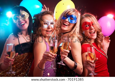 Portrait of happy young girls under masks on the party