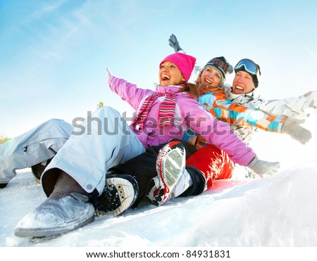 Group of  teenagers slide downhill in wintertime
