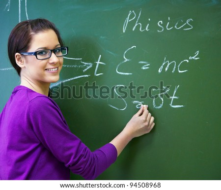 girl student wearing glasses at the blackboard writing formula