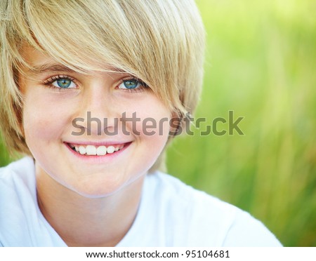 Portrait of fair-haired boy looking at camera outdoors