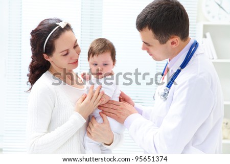 Mother holding baby for pediatrician to examine