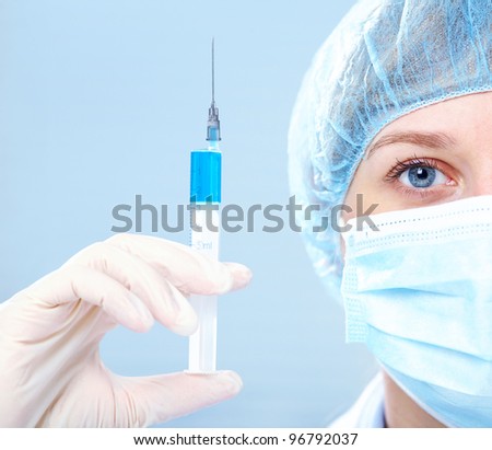 Close-up of a woman doctor's eye wearing a mask with syringe