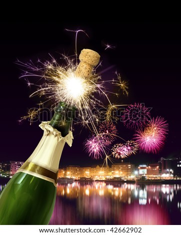 Champagne bottle cork popping against sparkling New Year fireworks