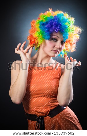 young beauty woman in multicolored clown wig smiling on black background