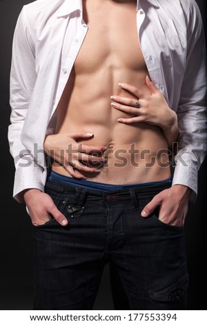 Woman\'s hands on a sexy man\'s torso on a black background