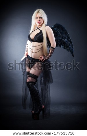 Woman in the lingerie with black angel wings against the black background