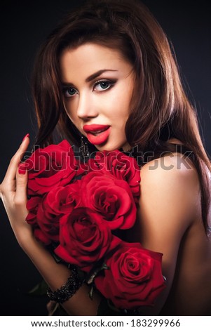 Stylish beautiful young woman holding red roses bouquet, tender flowers in hands, brunette female over dark background