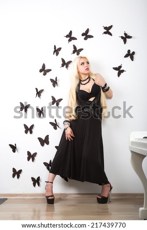 beautiful young attractive woman in evening dress and piano in a light room