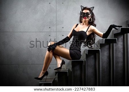 sexy woman in catwoman suit lying on stairs at backyard of building