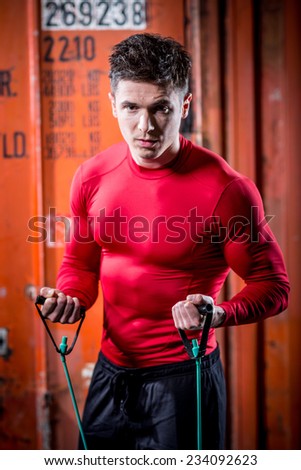muscular super-high level handsome man pulls rubber bands and posing