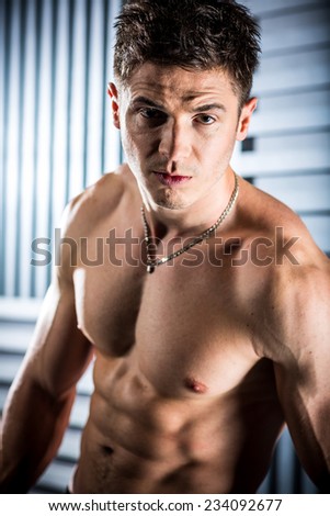 Sexy fashion portrait of a hot male model with muscular body posing in studio.Glamour colors