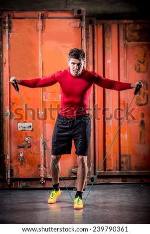 muscular super-high level handsome man pulls rubber bands and posing