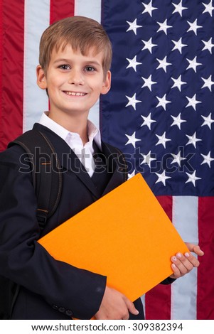 schoolboy is holding an orange book against USA flag