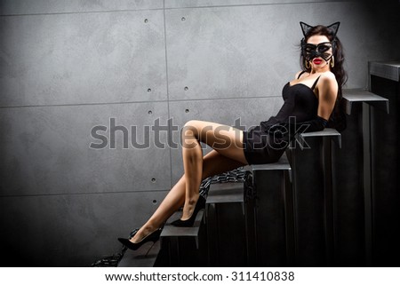 sexy woman in catwoman suit lying on stairs at backyard of building