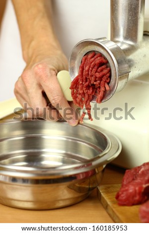 Mincing beef by meat grinder. Making enchilada tortilla with beef.