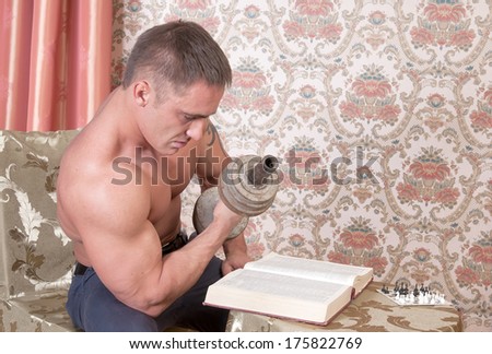 Strong man reading a book and trains the muscles