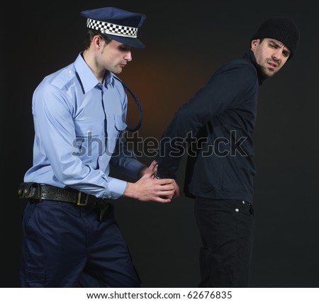 Police officer arresting a thief. Dark background.