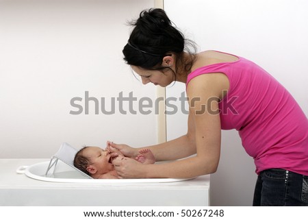 High key shot of a woman bathing her cute baby boy in a tub.